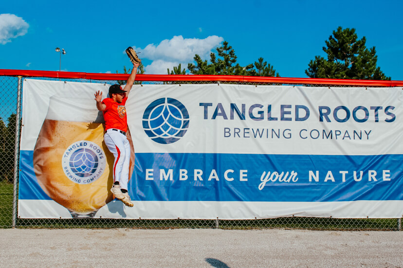 pistol shrimp outfielder catching ball against tangled roots brewing company banner