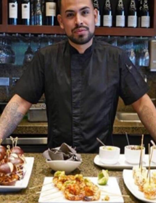 chef Jose Guerrero standing in front of variety of food dishes